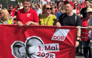 Lisa Paus läuft hinter dem Transparent des DGB.