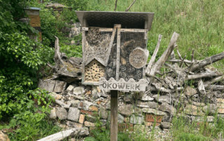 Bienenstock mit Schild, auf dem "Ökowerk" steht.